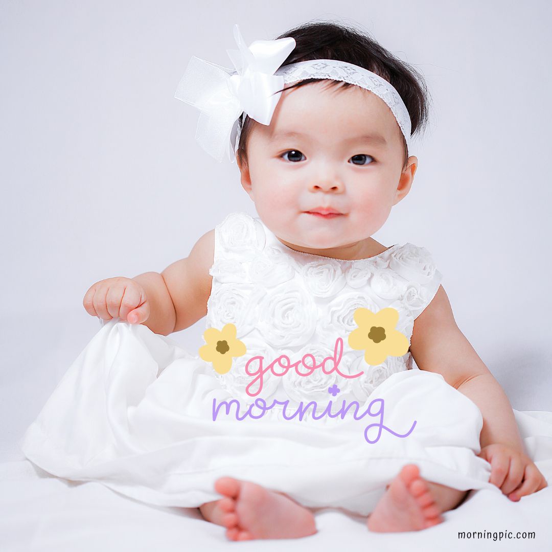 A baby girl wearing a white dress and a white headband with a bow sits against a white background. She has a serious expression and holds the hem of her dress. The text "good morning" in pastel colors and flower graphics is overlaid on the image, perfect for Good Morning Baby Images HD collections.