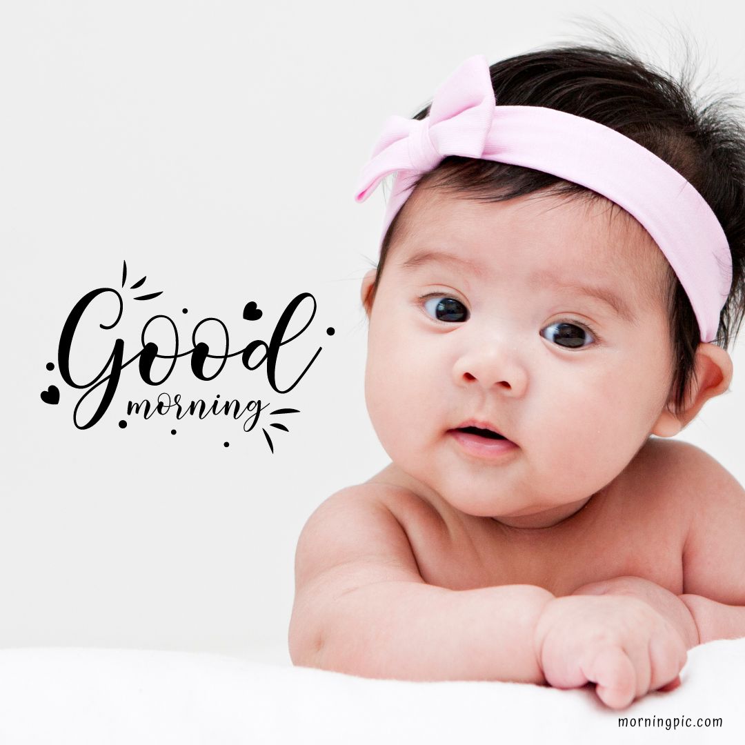 A baby girl wearing a pink headband with a bow looks towards the camera. Lying on her stomach with a curious expression, she radiates charm. The text "Good Morning Baby Girl" is written in a stylish font next to her.