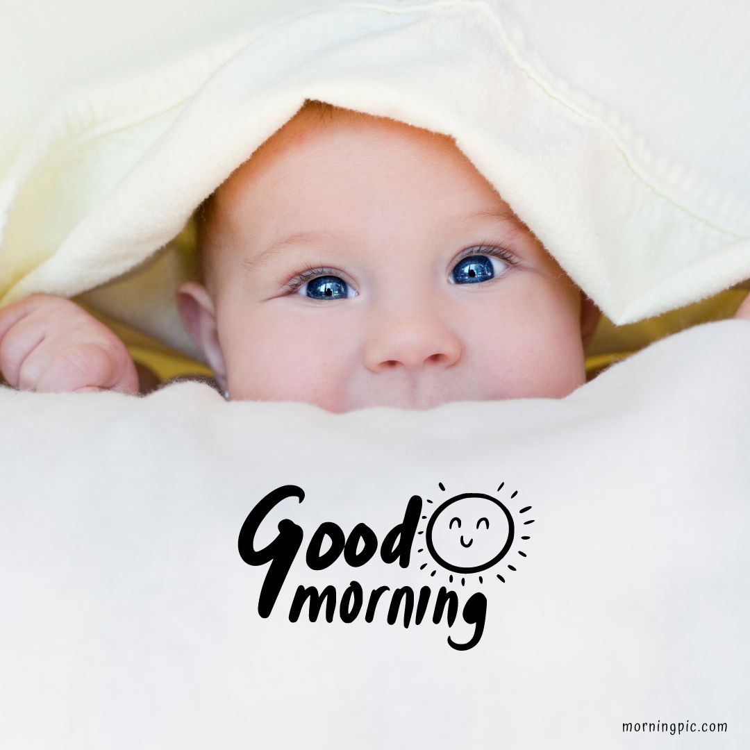 A baby with blue eyes peeks out from under a light yellow blanket, looking directly at the camera. The text "Good Morning Baby Images" with a smiling sun doodle accompanies the image.