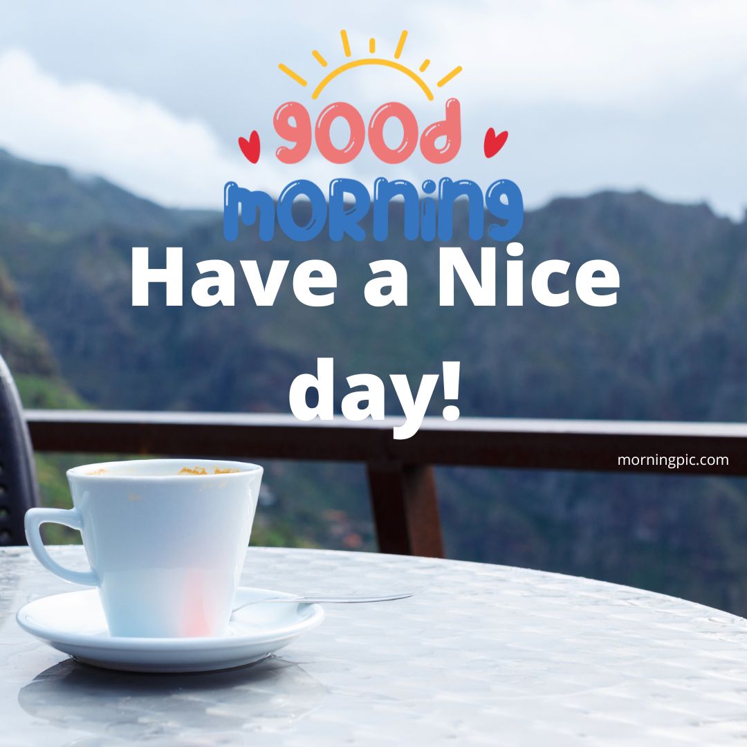 A white cup on a saucer sits on a patio table, with a scenic mountain landscape in the background. Above, colorful text reads "Good Morning" with a sun illustration, and below it says "Have a Nice day!" The image is from morningpicdaily.com. Perfect for those searching for good morning have a nice day images!