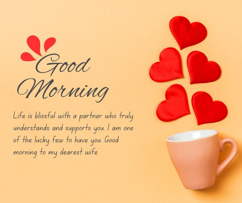 A peach-colored coffee cup on a light orange background, with red heart-shaped decorations scattered around. The image includes the text 'Good Morning' and 'Life is blissful with a partner who truly understands and supports you. I am one of the lucky few to have you. Good morning to my dearest wife,' making it perfect for good morning messages for wife image.