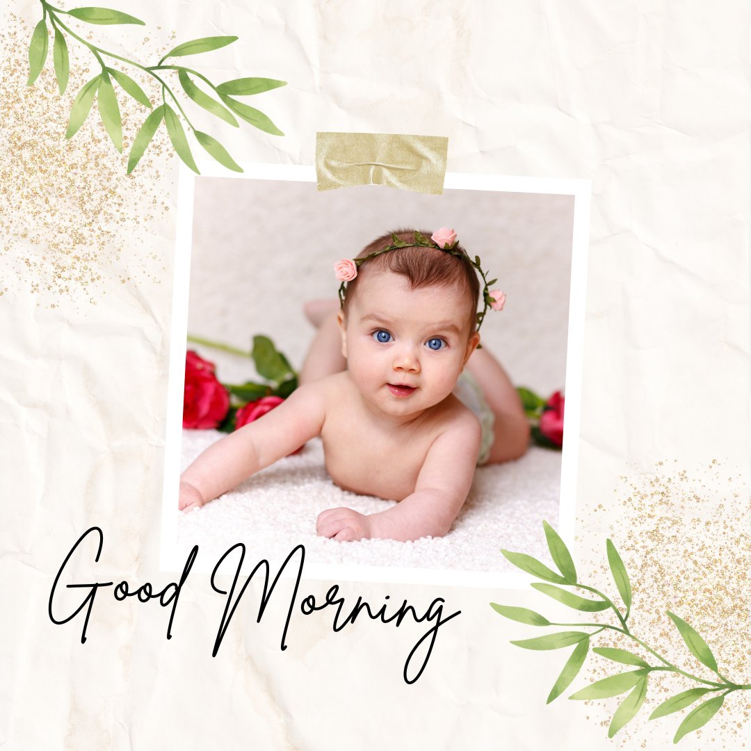 A baby with bright blue eyes and a floral headband lies on their stomach, looking up. The child is surrounded by rose petals on a soft, white surface. The photo is framed with green leaves and glitter accents on a textured background, with "Good Morning Baby Images" text below.