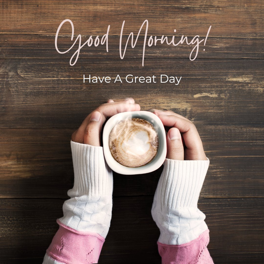 Hands holding a cup of coffee with a heart-shaped design, over a wooden table, with Good Morning and Have A Great Day text.