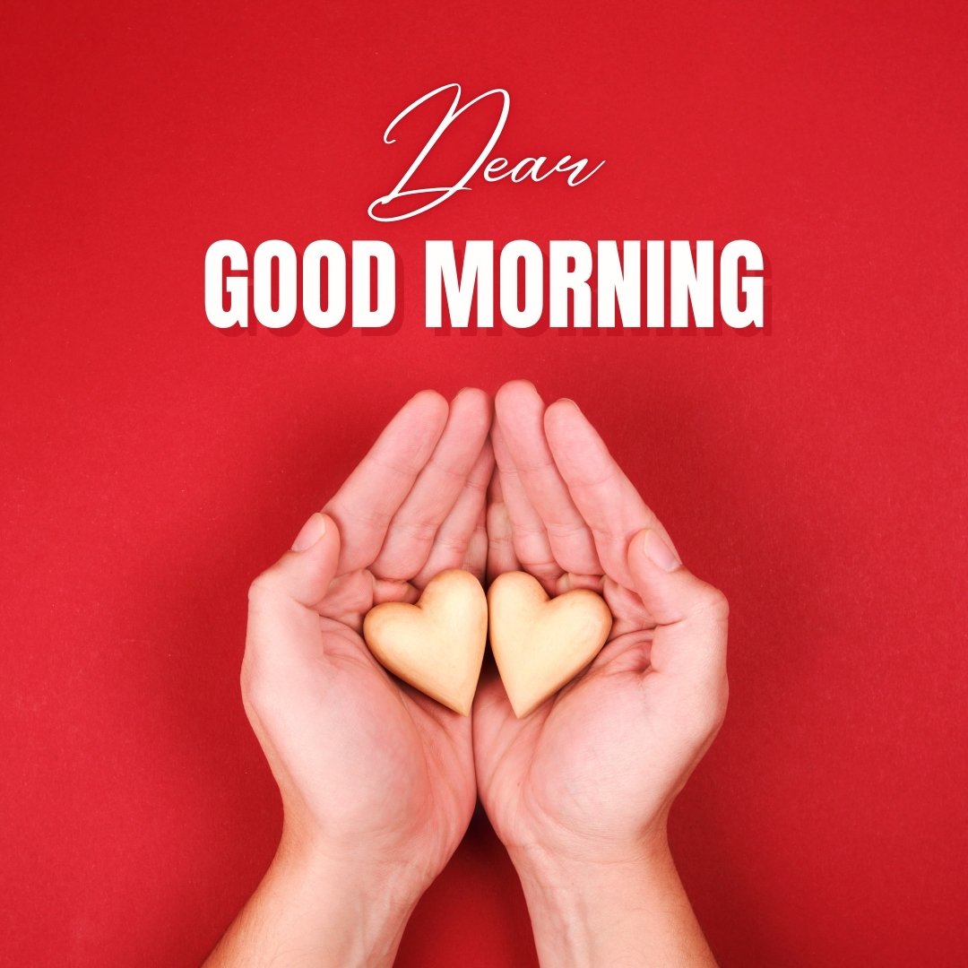 Good morning dear image featuring two hands holding heart-shaped cookies against a vibrant red background, symbolizing love and care in the morning.