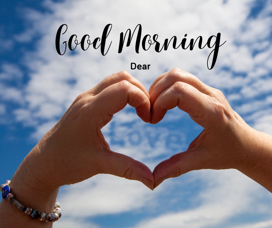 Good morning dear image featuring a heart shape made with hands against a blue sky with fluffy clouds, conveying love and positivity.