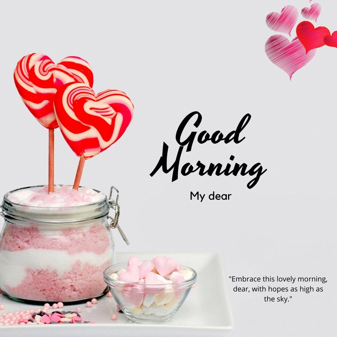 Good morning dear image showcasing a whimsical arrangement with two red and white swirled heart-shaped lollipops in a jar of pink sugar, accompanied by a bowl of pink heart-shaped candies and floating heart illustrations, with the greeting 'Good Morning My dear' and an inspirational quote.