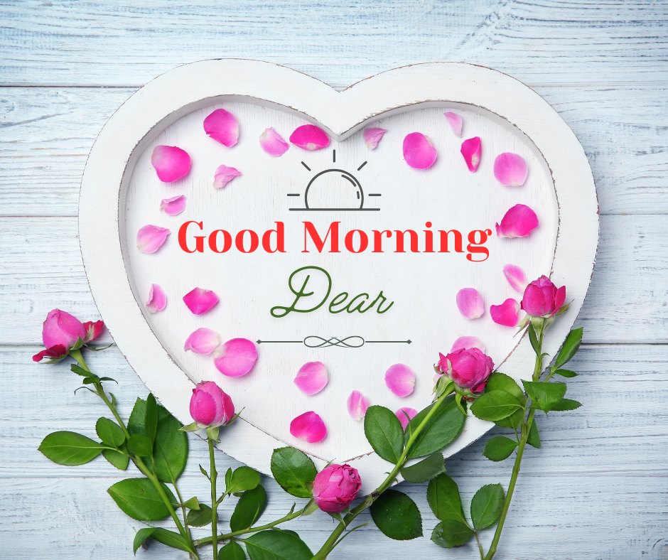 Good morning dear images featuring a rustic heart-shaped wooden frame sprinkled with vibrant pink rose petals, placed on a weathered white wooden background. Next to the frame are fresh pink rose buds, complementing the soft and romantic theme.