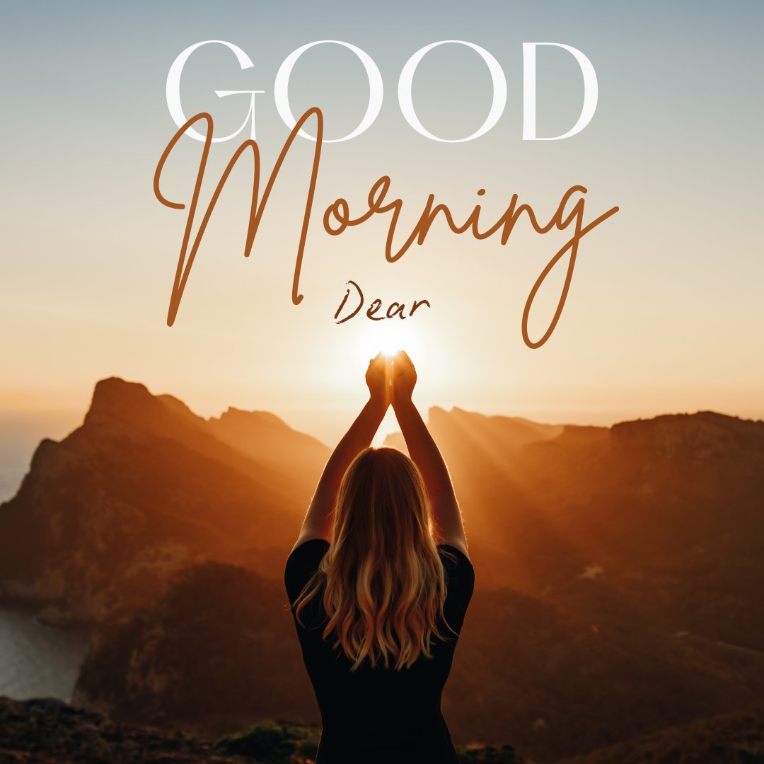 Good morning dear images featuring a woman greeting the sunrise in a meditative pose atop a mountain. The early morning light casts a golden glow over the rugged landscape, enhancing the serene atmosphere. Elegant script overlays reading 'Good Morning Dear' add a touch of inspiration.