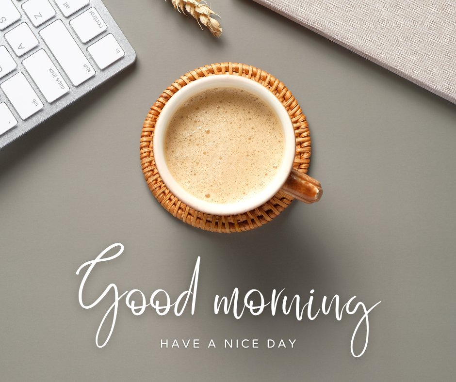 A coffee cup in a wicker coaster sits on a gray surface next to a corner of a keyboard and a light brown object. The text reads "Good morning" in script font and "HAVE A NICE DAY" in capital letters below it. A small ear of wheat is also visible, creating serene images to start your day positively.